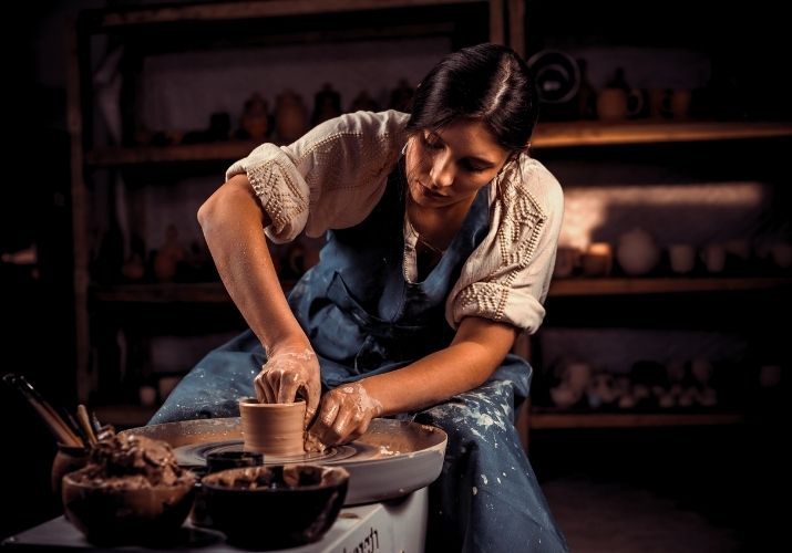 Imagem das mãos de uma escultora fazendo um pequeno e simples jarro de barro, com intensidade e delicadeza.