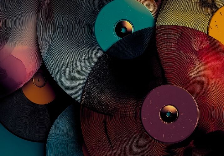 Vários discos de vinil coloridos, as cores se misturam, o quente com o frio, é alegre mas não é gritante.
